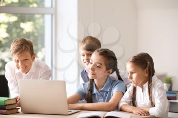 Cute little pupils with laptop in classroom�