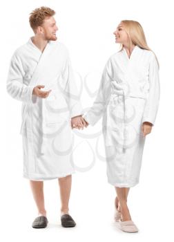 Happy young couple in bathrobes on white background�