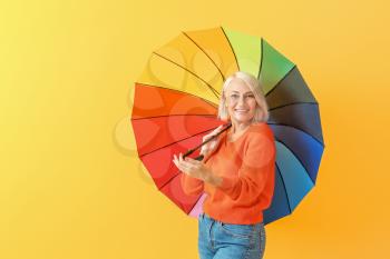 Stylish mature woman with umbrella on color background�