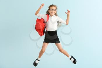 Jumping little schoolgirl on color background�