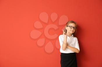 Little schoolgirl with raised index finger on color background�