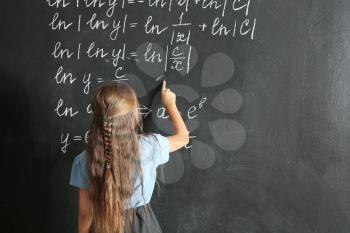 Little schoolgirl near blackboard in classroom�