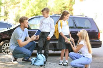 Parents getting their children ready for school outdoors�