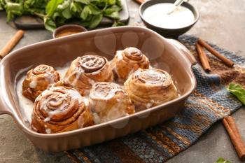 Baking tray with tasty cinnamon buns on table�