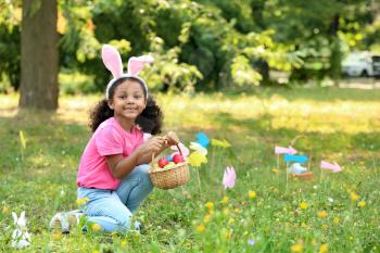 Little African-American girl gathering Easter eggs in park�