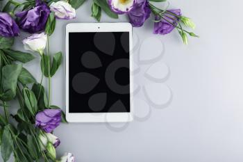 Modern tablet computer with flowers on grey background�
