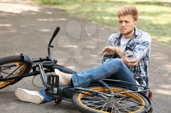 Young man fallen off his bicycle outdoors�