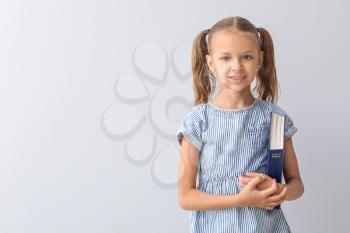 Cute little girl with Bible on light background�