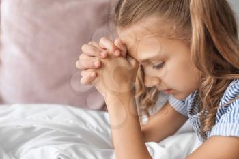 Cute little girl praying in bedroom�