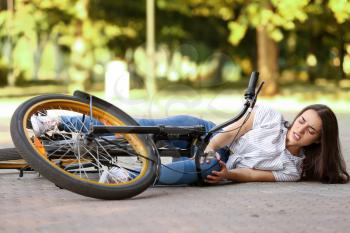 Young woman fallen off her bicycle outdoors�