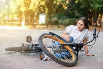 Young woman fallen off her bicycle outdoors�
