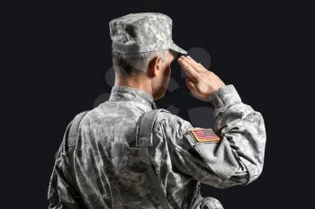 Saluting male soldier on dark background�