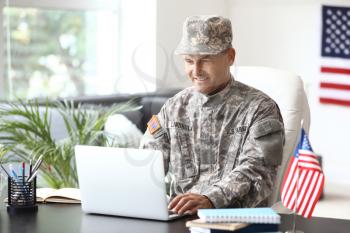 Mature male soldier working with laptop in headquarters building�