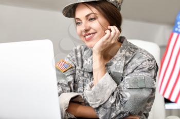 Young female soldier working with laptop in headquarters building�