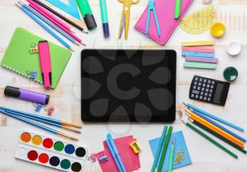 Set of school supplies with tablet computer on white wooden background�