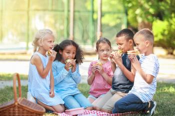 Cute little children having lunch in park�