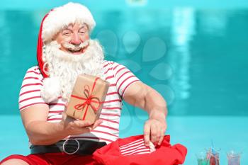 Santa Claus with gifts near swimming pool at resort�