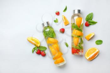 Bottles of tasty infused water on light background�