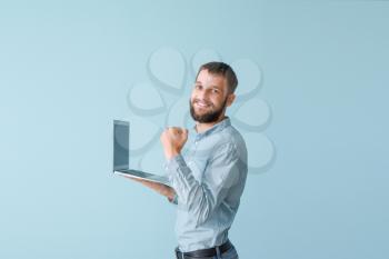 Portrait of happy young man with laptop on color background�