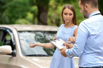 Young woman and insurance agent near damaged car outdoors�