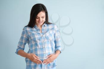 Young pregnant woman on color background�