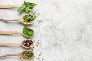 Spoons with different fresh herbs and spices on light background�