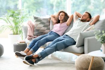 Happy young couple relaxing on sofa at home�
