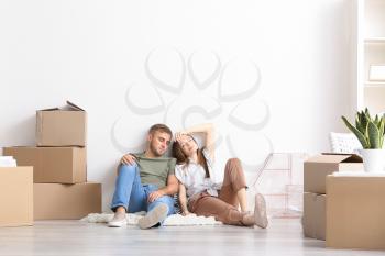 Tired couple sitting on floor after moving into new house�