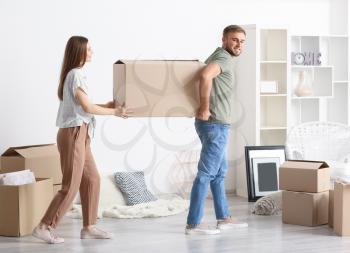 Young couple carrying boxes after moving into new house�