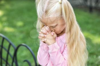 Cute little girl praying outdoors�