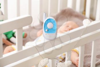 Modern baby monitor on crib of sleeping infant�