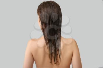 Beautiful young woman after washing hair against grey background, back view�