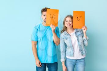 Young couple with emoticons against color background�