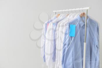 Rack with clothes after dry-cleaning on light background�