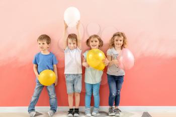 Cute little children with air balloons near color wall�