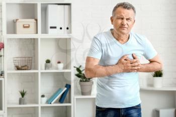 Mature man suffering from heart attack at home�