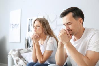 Religious couple praying to God at home�