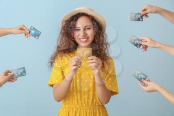 Young African-American woman and hands with credit cards on color background�