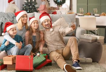 Happy family with Christmas gifts taking selfie at home�
