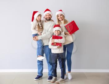 Happy family with Christmas gifts near light wall�