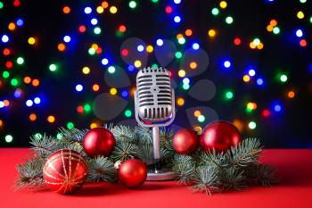 Retro microphone with Christmas decor on table against defocused lights�