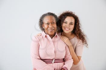 Portrait of African-American woman with her daughter on light background�