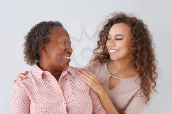 Portrait of African-American woman with her daughter on light background�