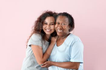 Portrait of African-American woman with her daughter on color background�