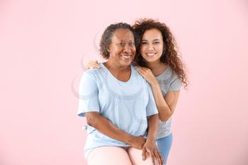 Portrait of African-American woman with her daughter on color background�