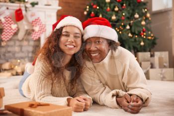 Portrait of African-American woman and her daughter in Santa hats at home�