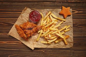 Tasty fast food with tomato sauce on wooden table�