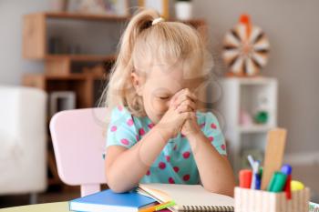 Cute little girl praying at home�