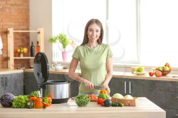 Woman cutting vegetables for stewing in multi cooker�