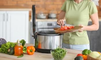 Woman using modern multi cooker in kitchen�